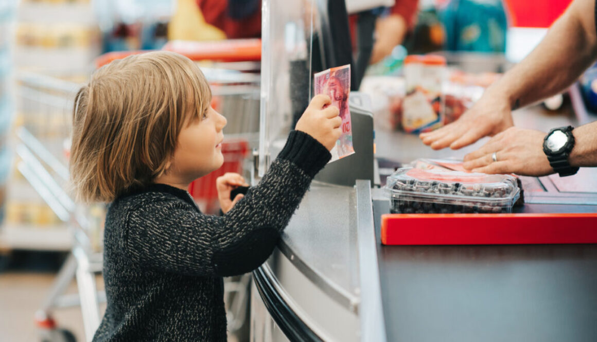 photo of little boy giving money over counter in store to buy something
